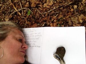 portrait photo of tiffany on a sketchbook on the forest floor facing a flint figurehead